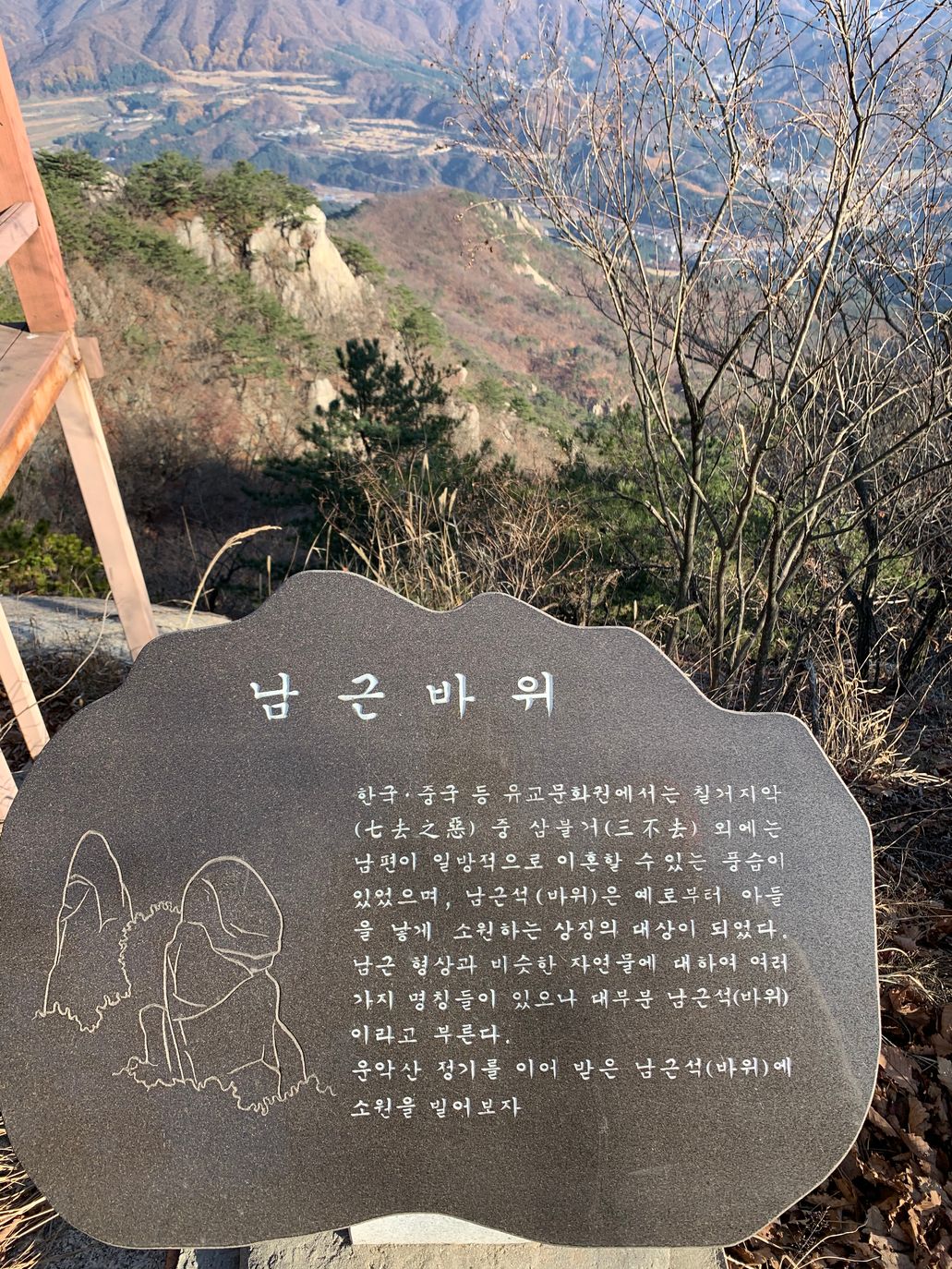 남근바위 안내판과 그 아래로 내려다보이는 마을